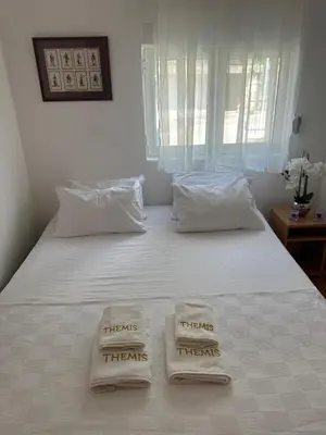two towels on a white bed with a window at Themis Apartment in Kotor