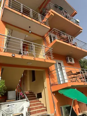 an orange building with stairs and an umbrella at Themis Apartment in Kotor