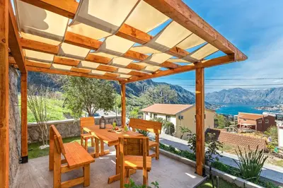 a wooden pergola on a patio with a table and chairs at Apartment Petar 1 in Kotor