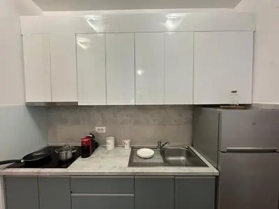 a kitchen with white cabinets and a sink and a refrigerator at Studio Lemar in Budva