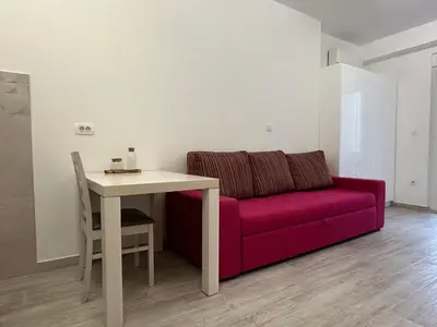 a living room with a red couch and a table at Studio Lemar in Budva