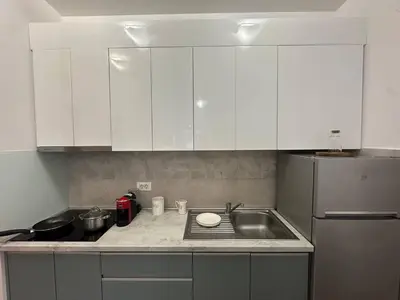 a kitchen with white cabinets and a sink and a refrigerator at Studio Lemar in Budva