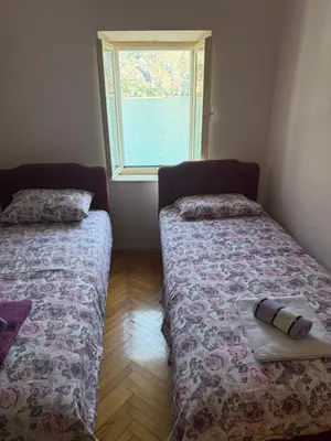 two beds in a room with a window at Iva apartment in Kotor