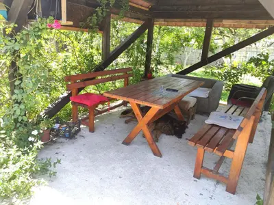 a wooden picnic table and two benches under a pavilion at Green Valley GV in Kotor