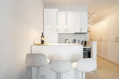 a white kitchen with white cabinets and white stools at Przno Apartments by In Property in Pržno