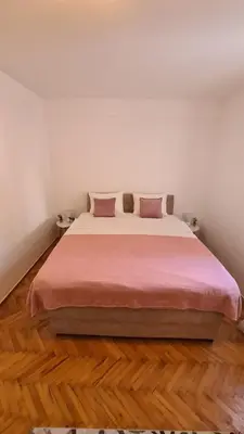 a bedroom with a large bed with pink sheets at Boka apartment in Kotor
