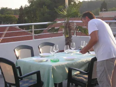a man standing around a table with wine glasses at Apartmen Donji Stoj in Donji Štoj