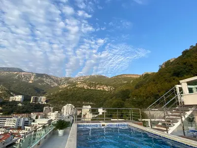 a swimming pool on top of a building with mountains at Ponta Nova One bedroom Apartment with Sea view in Budva