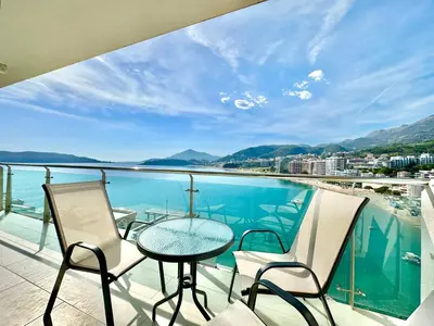 a balcony with a table and chairs and a view of the water at Ponta Nova One bedroom Apartment with Sea view in Budva