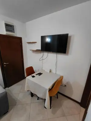 a room with a table and a tv on the wall at Luna Apartman in Kotor