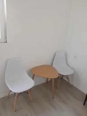 two white chairs and a table in a room at Mara in Podgorica