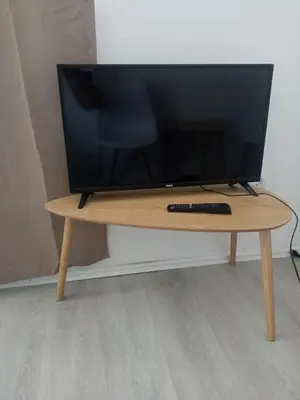 a television on a wooden table with a remote control at Mara in Podgorica