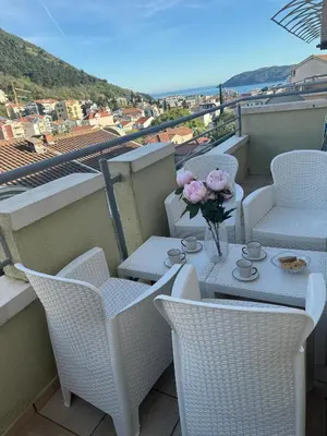 a table and chairs with a vase of flowers on a balcony at MBD apartment Budva in Budva