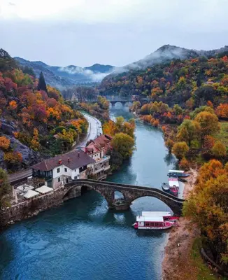 a river with a bridge and a boat in the water at Rijeka crnojevica in Cetinje