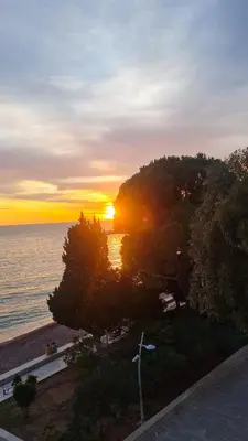 a sunset over a body of water with a windmill at La Vista Apartment in Petrovac na Moru