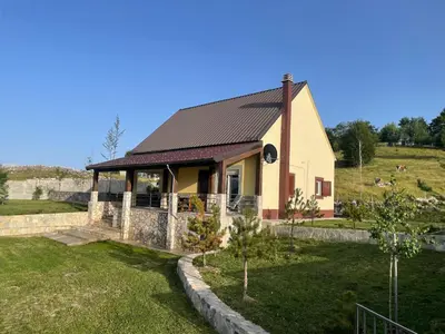 a small yellow house with a black roof at Holiday House Korita in Podgorica