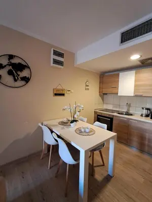 a kitchen with a white table and white chairs at Holiday Home Apartment in Budva
