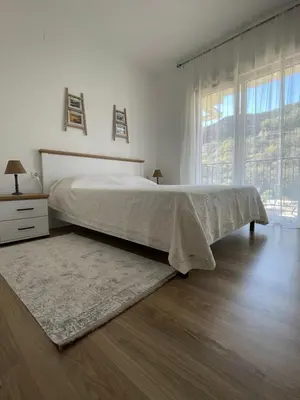 a white bedroom with a bed and a large window at Listik Apartments in Becici