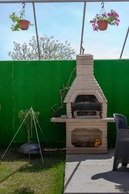 a fireplace in a backyard with a green wall at Vila Apartmani Astoria in Podgorica