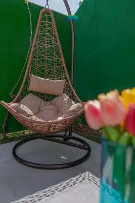 a hanging chair with pillows and a vase of flowers at Vila Apartmani Astoria in Podgorica