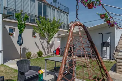 a swing in a yard with a table and chairs at Vila Apartmani Astoria in Podgorica