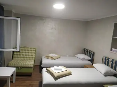 a room with two beds and a chair and a table at Studio Kaća 2 in Cetinje