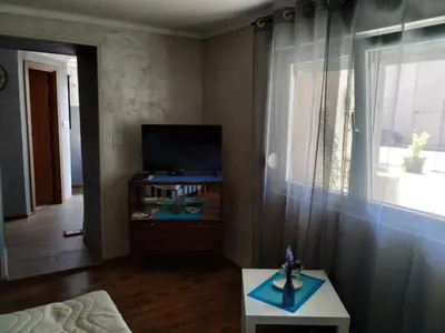 a living room with a flat screen tv and a table at Studio Kaća 2 in Cetinje