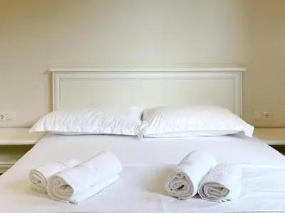 a white bed with three rolled towels on it at Guest House Bonaca in Ulcinj