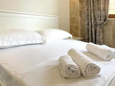 a white bed with two rolled towels on it at Guest House Bonaca in Ulcinj