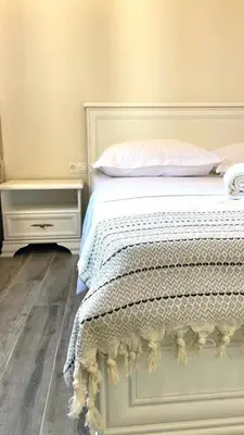 a bed with a white comforter and two night stands at Guest House Bonaca in Ulcinj