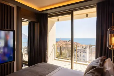 a bedroom with a large window with a view of the ocean at Merit Starlit Hotel & Residences in Budva