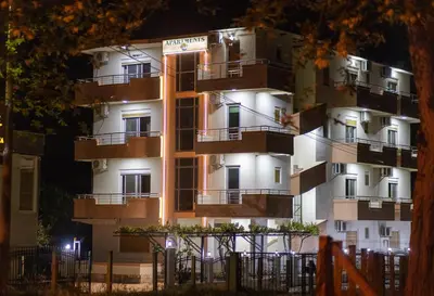 a tall white building with balconies at night at Villa Elezi in Ulcinj