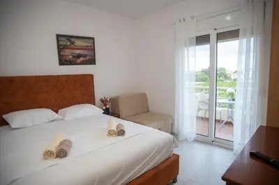a bedroom with a bed and a chair and a balcony at Villa Elezi in Ulcinj