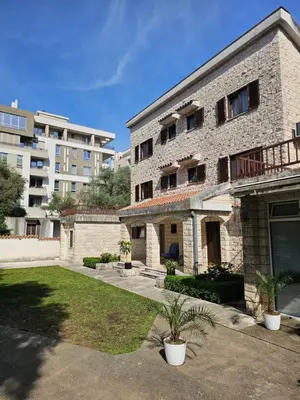 a large brick building with plants in a yard at Bravo Plus in Budva