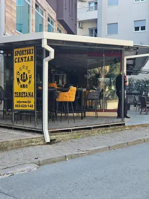 a man standing in front of a restaurant with yellow chairs at Bravo Plus in Budva