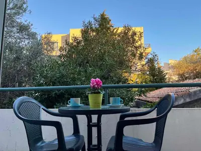 a table with two chairs and a flower on a balcony at Apartments and Room MV in Petrovac na Moru