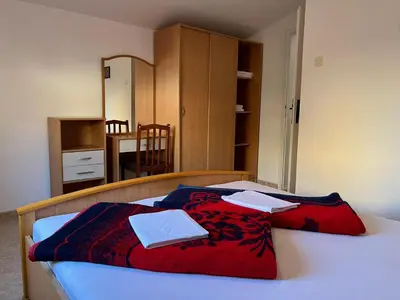 a bedroom with a bed with a red blanket on it at Apartments and Room MV in Petrovac na Moru