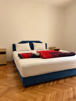a large bed in a room with a wooden floor at Apartments and Room MV in Petrovac na Moru