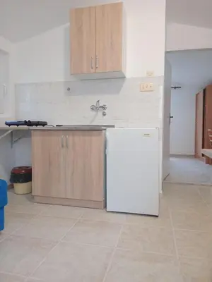 a kitchen with a white refrigerator and wooden cabinets at Apartments and Room MV in Petrovac na Moru