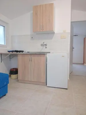 a kitchen with a white refrigerator and wooden cabinets at Apartments and Room MV in Petrovac na Moru