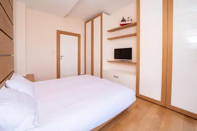a bedroom with a white bed and a television at Villa Tivat Bay View in Kotor