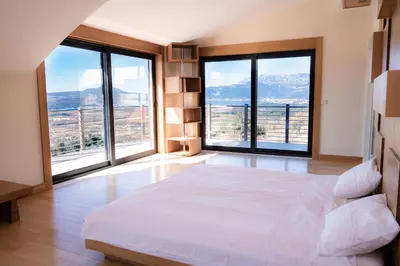 a bedroom with a large bed with large windows at Villa Tivat Bay View in Kotor