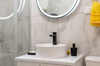 a white bathroom with a sink and a mirror at Apartment UR in Bar