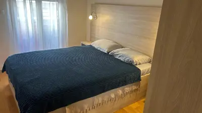 a bed with a blue blanket and pillows on it at Comfort Central Point apartment in Podgorica