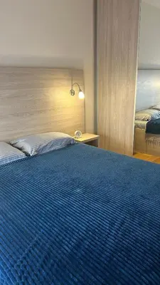 a bedroom with a large bed with a blue blanket at Comfort Central Point apartment in Podgorica