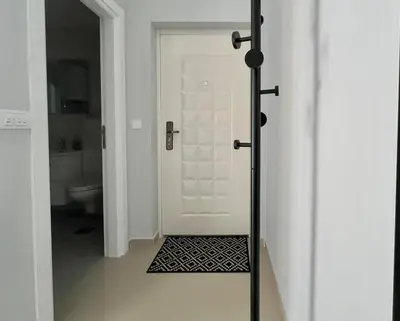 a bathroom with a white door and a black rug at Danver Apartment in Bar