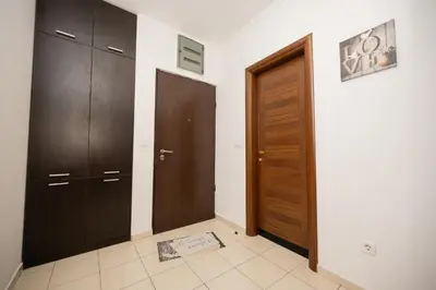 a hallway with two wooden doors and a tile floor at Apartman Klara Podgorica in Podgorica