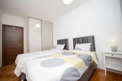 a bedroom with a bed with a white and yellow blanket at Apartman Klara Podgorica in Podgorica