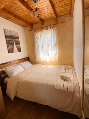 a bedroom with a large white bed with a window at Skadar Lake House Nature Nest in Virpazar