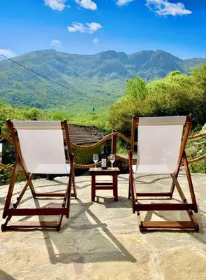 two chairs on a patio with a table and mountains at Skadar Lake House Nature Nest in Virpazar